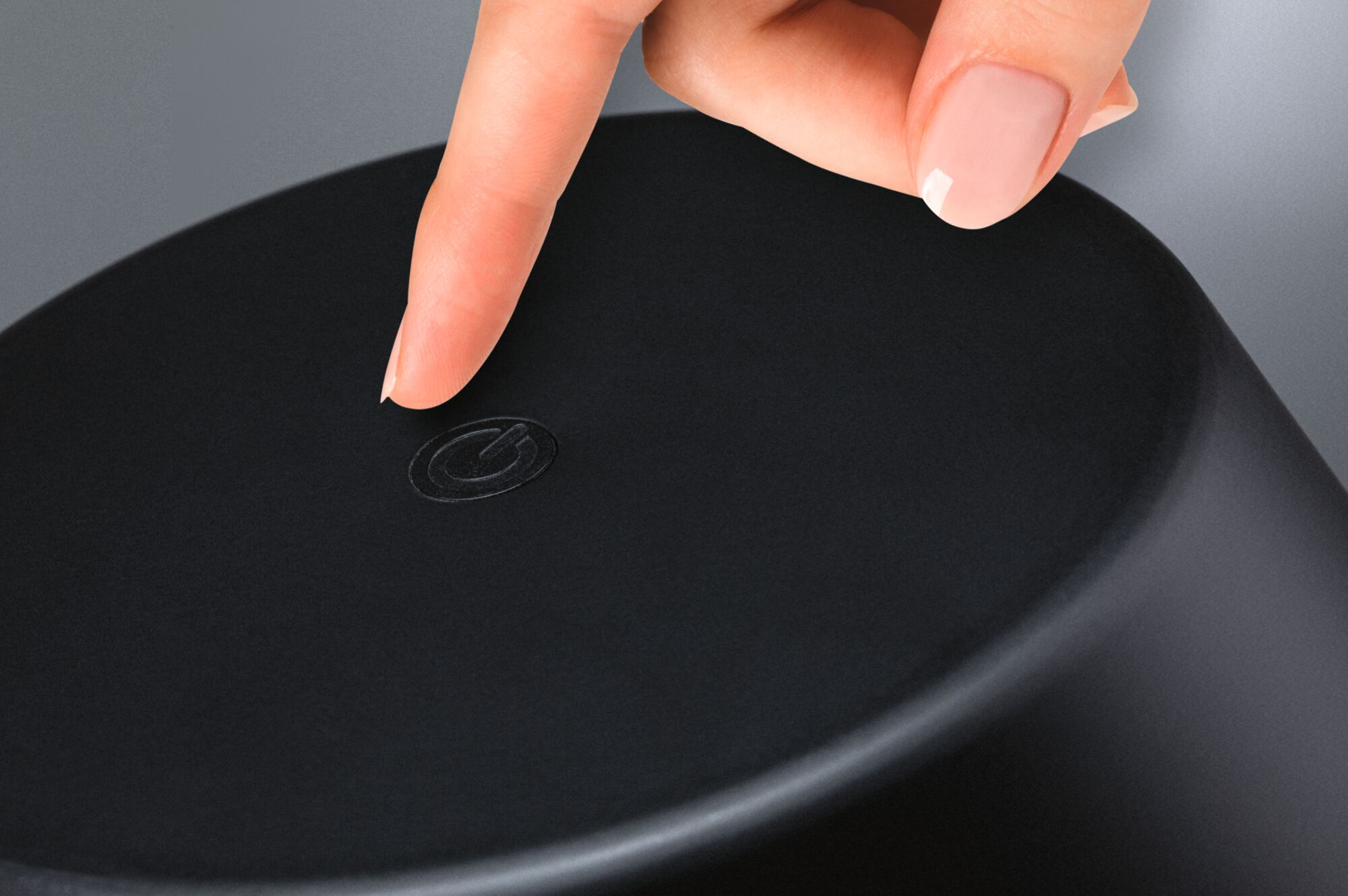 Palec naciska symbol zasilania na czarnym obiekcie.