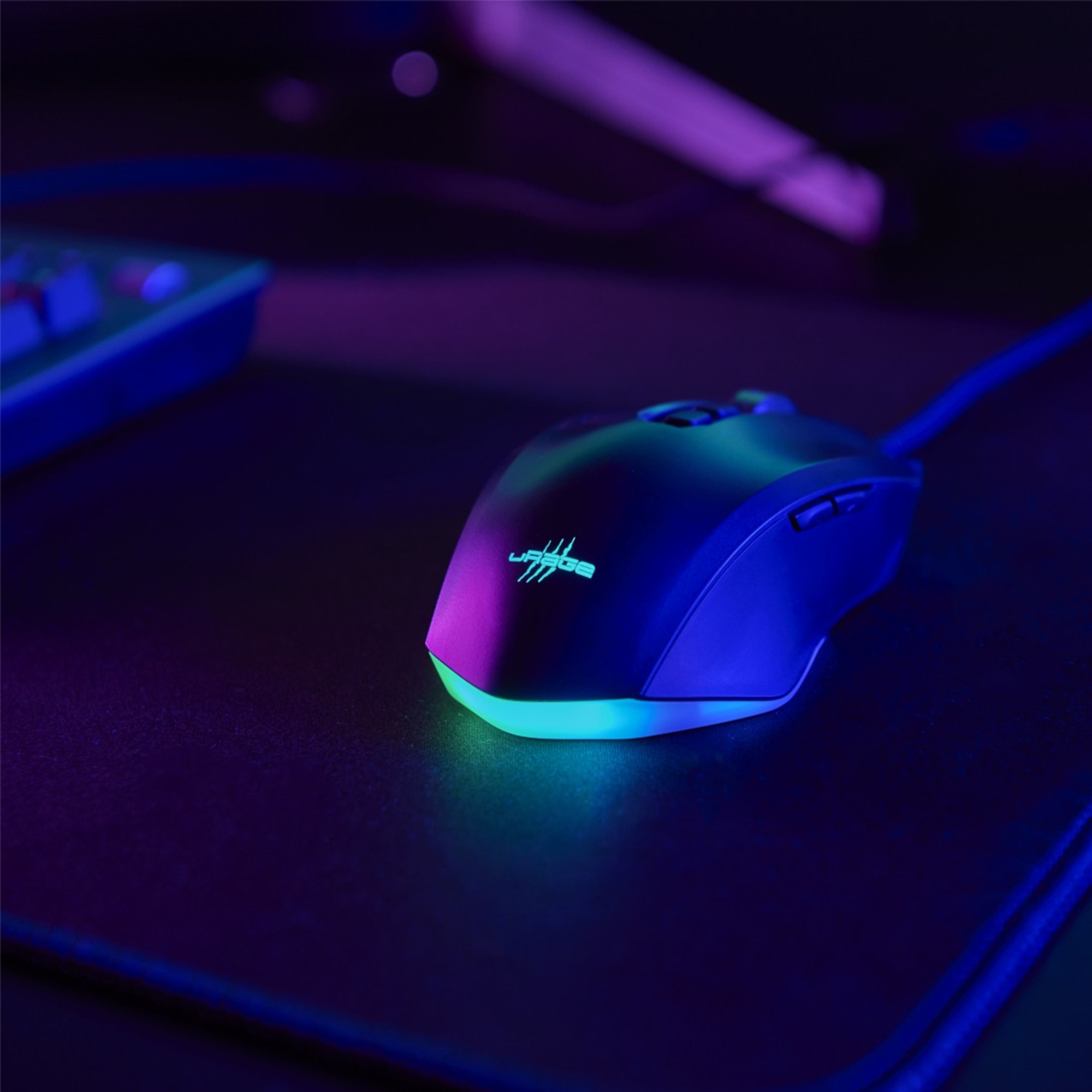 Un mouse da gaming scuro brilla di verde e blu su un tappetino nero.