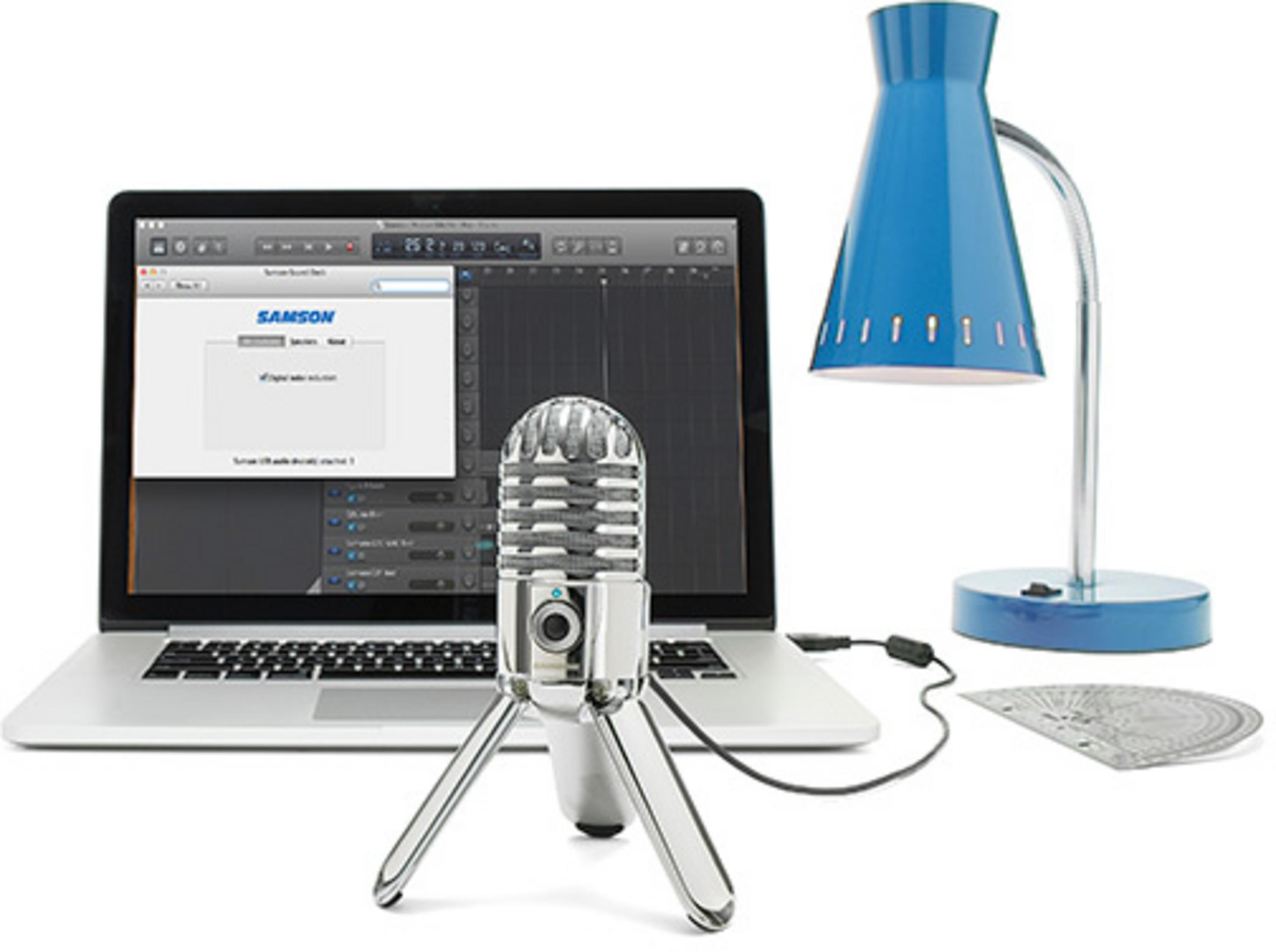 Ein silbernes Mikrofon steht vor einem Laptop mit Musiksoftware. Eine blaue Lampe steht daneben.