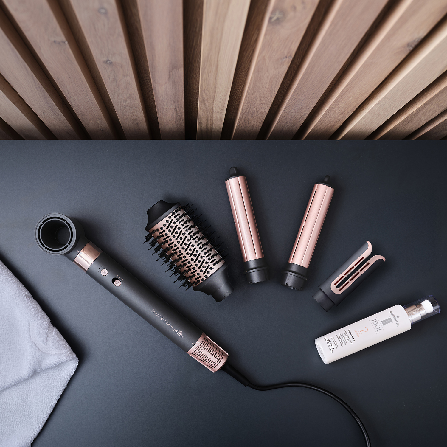 Hair dryer with attachments, towel, and bottle on a dark background.