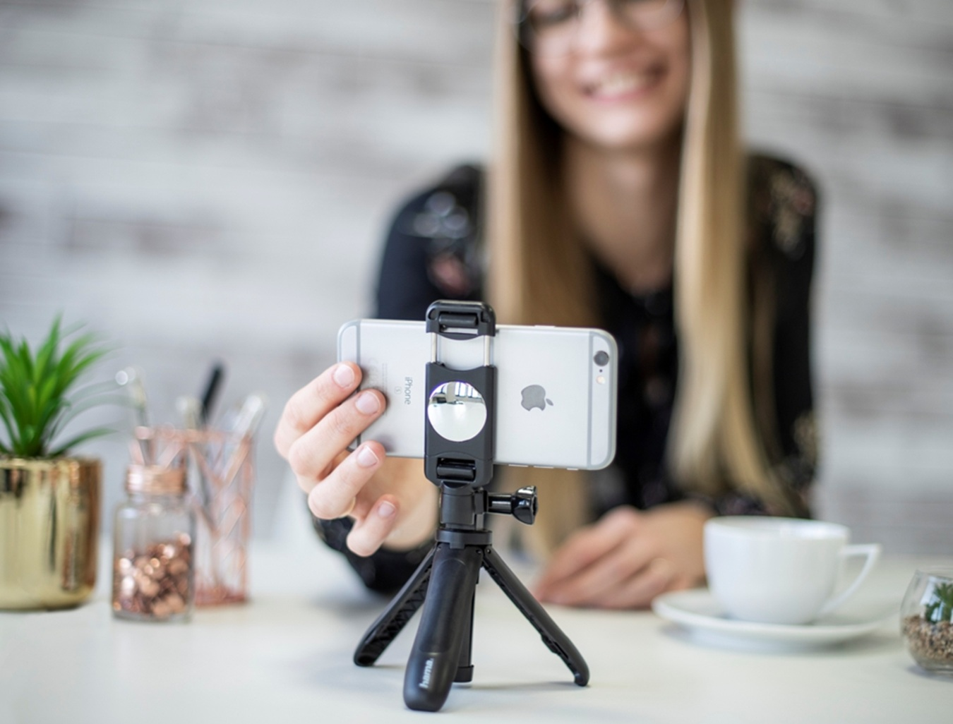 Una donna si filma con un iPhone su un treppiede. Sta sorridendo.