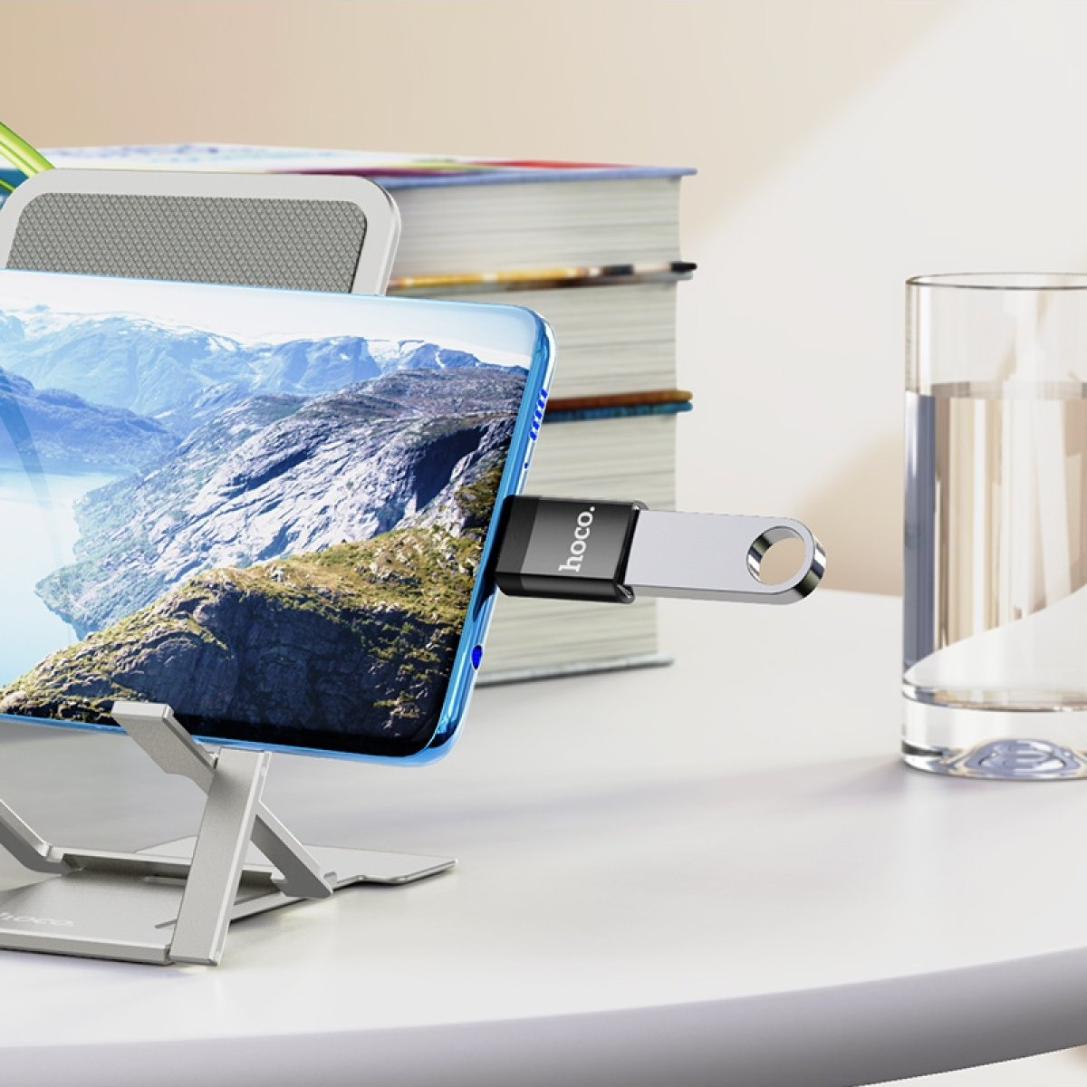 USB bellekli akıllı telefon, yanında kitaplar ve bir bardak su.