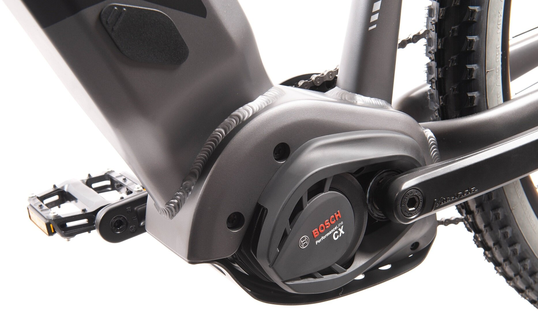 Zbliżenie jednostki napędowej roweru elektrycznego z silnikiem Bosch CX, łańcuchem i pedałami.