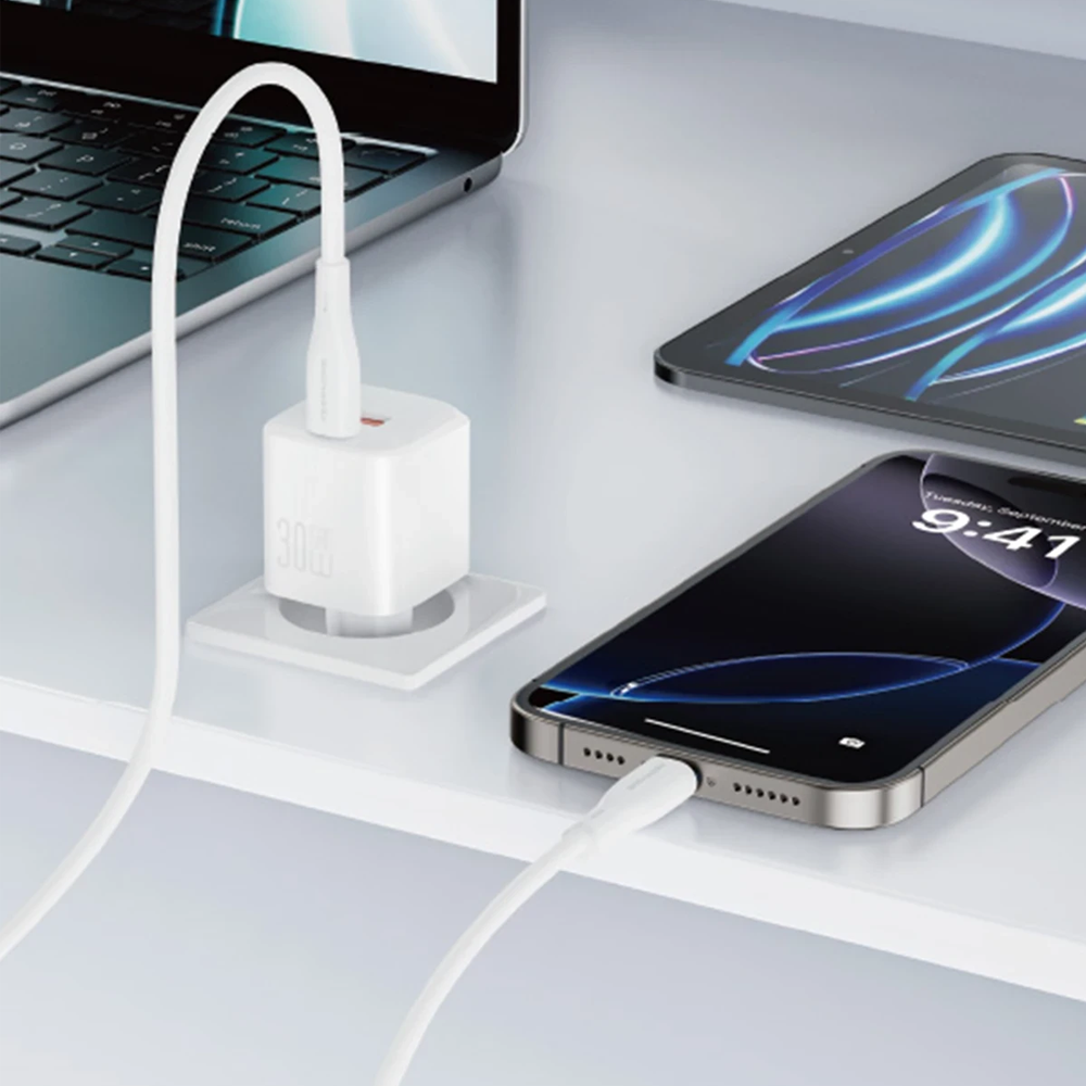 Beyaz bir 30W şarj cihazı, dizüstü bilgisayarın yanında bir akıllı telefon ve tableti şarj ediyor.