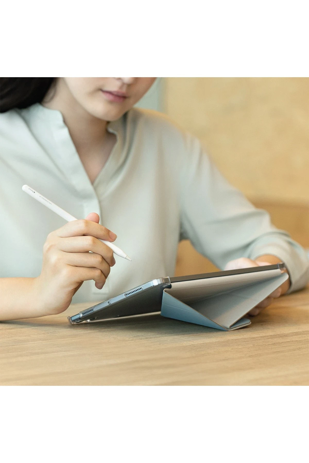 Kadın, mavi standlı bir tabletin üzerinde beyaz bir kalem tutuyor.