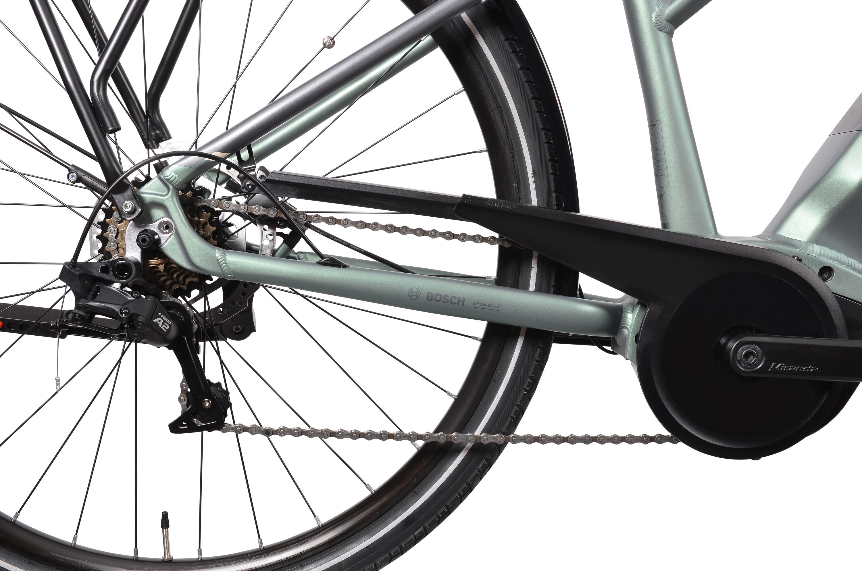 Zbliżenie napędu srebrnego roweru elektrycznego: łańcuch, zębatki, kaseta, osłona i logo Bosch.