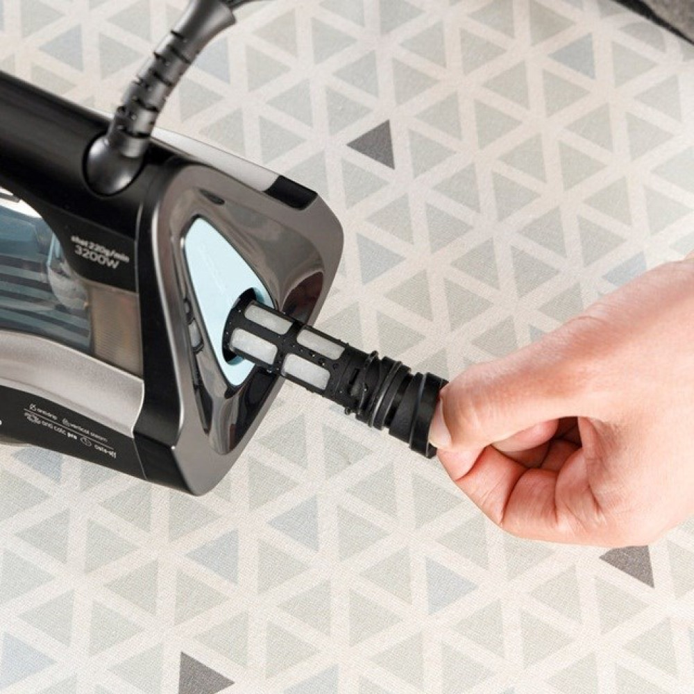 Ręka wyjmuje czarny filtr z żelazka parowego.