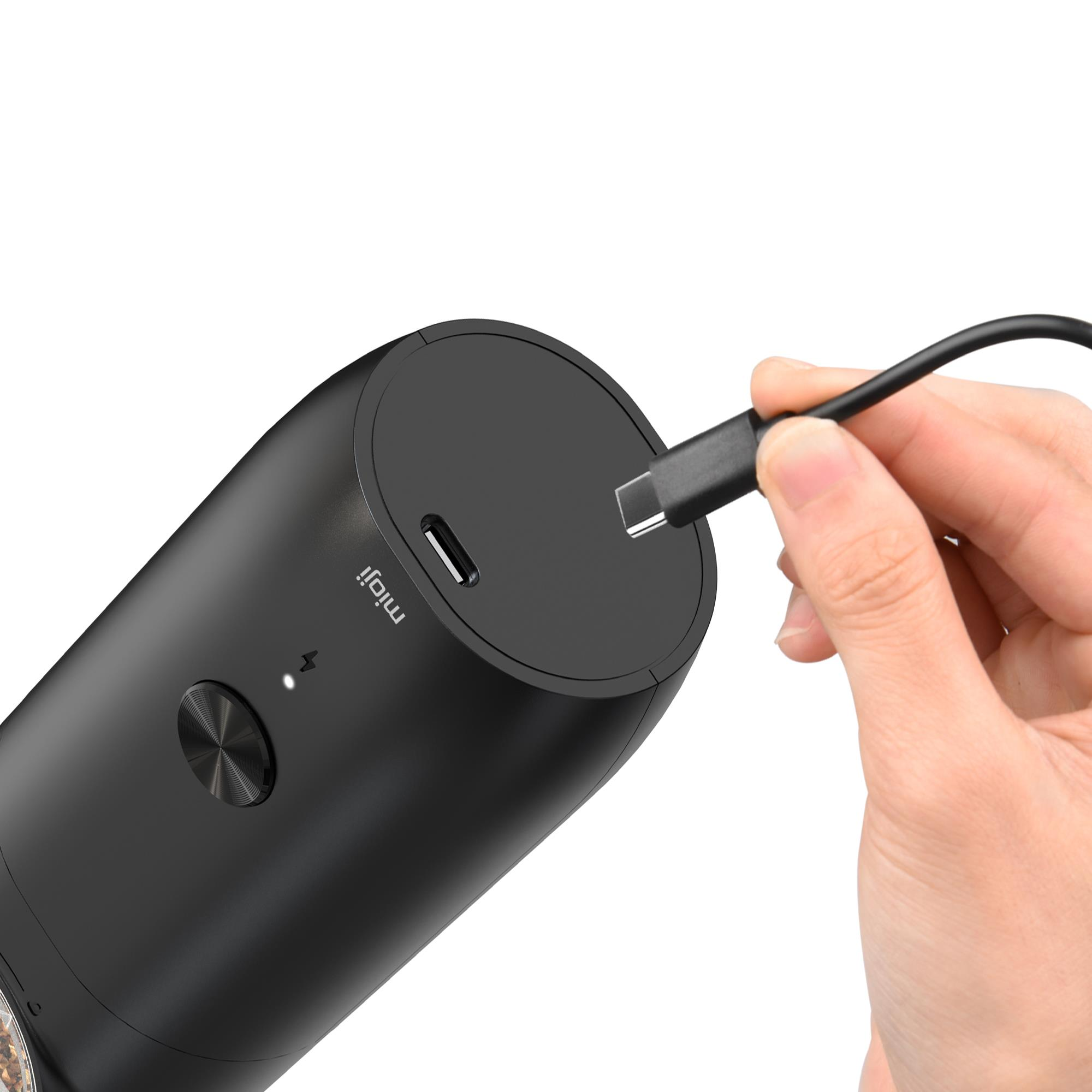 Bir el, siyah bir cihaza siyah bir USB-C kablosu takıyor.