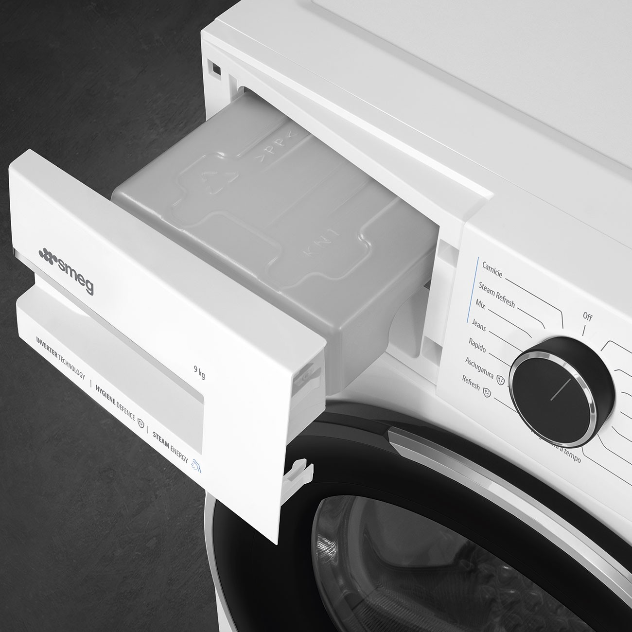 Cassetto detersivo aperto di una lavatrice Smeg bianca con selezione programmi.