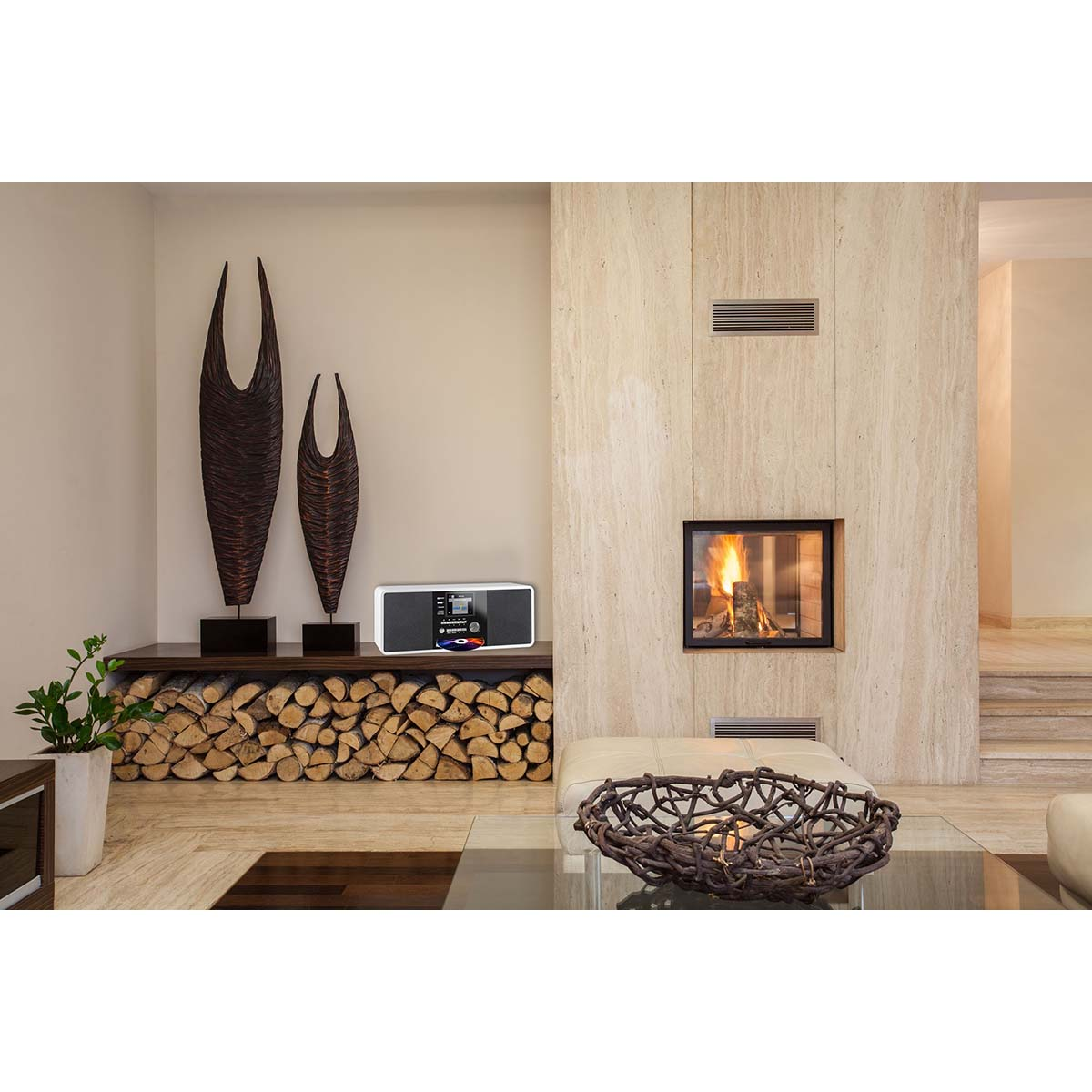 Una sala de estar moderna con chimenea, leña apilada y piezas de arte.