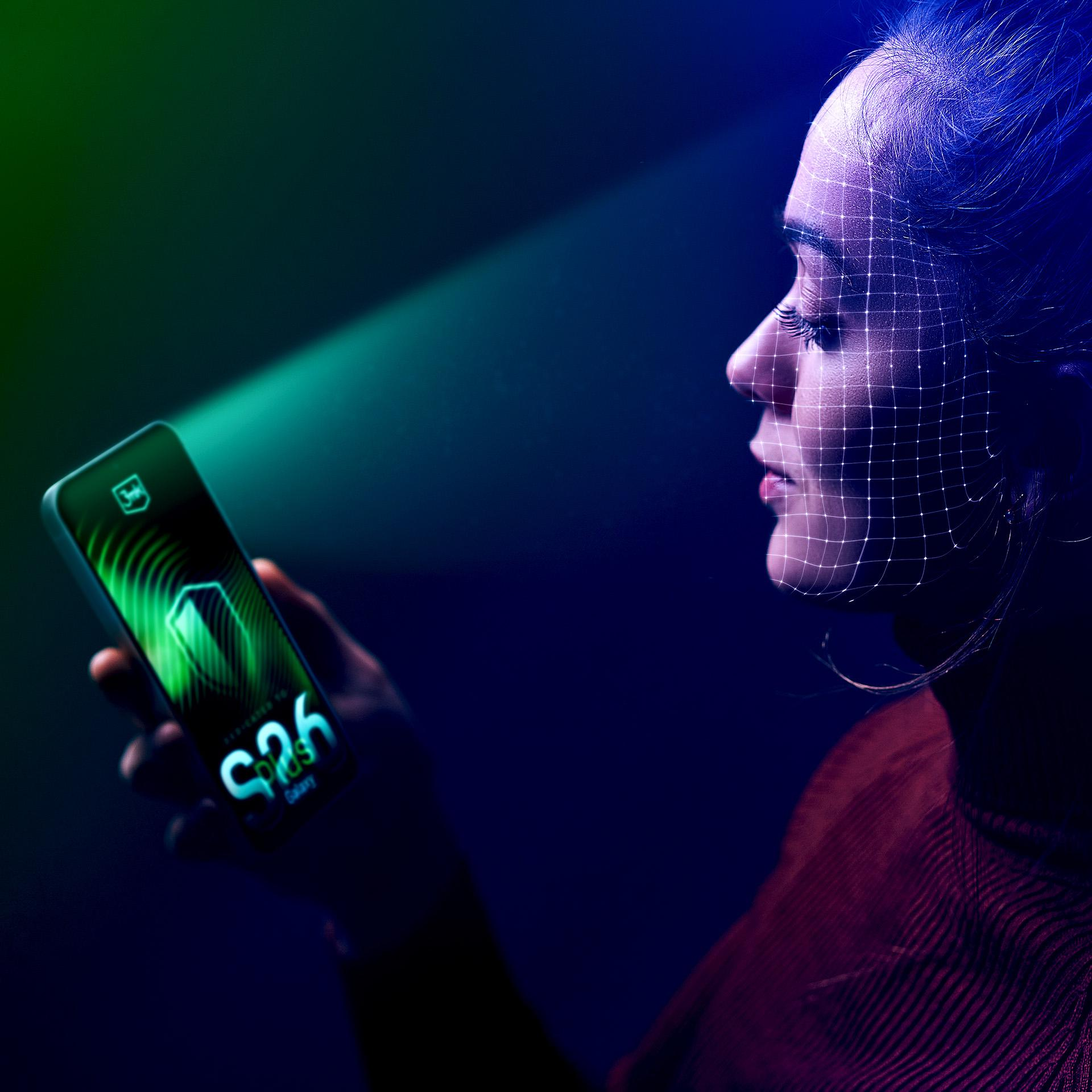 Twarz kobiety z nałożoną siatką, trzymająca telefon z zielonym ekranem, reprezentująca technologię rozpoznawania twarzy.