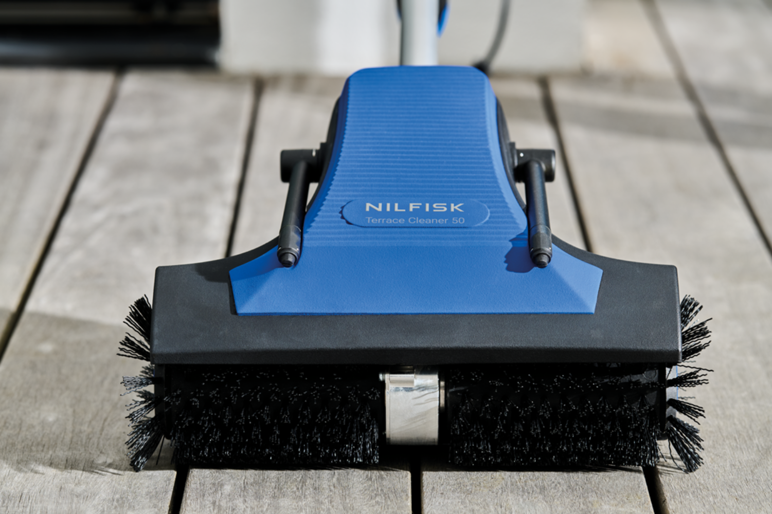 Blaue Nilfisk Terrassenreiniger 50 mit Bürsten auf Holzdeck.