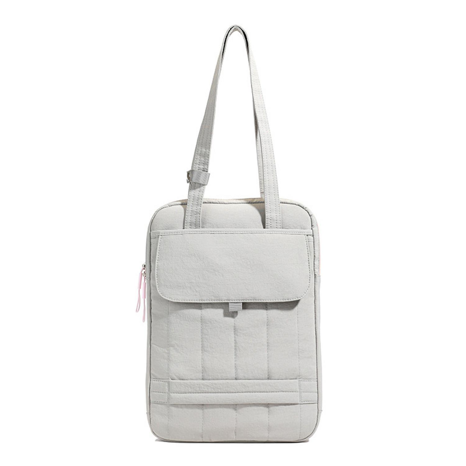 Eine gesteppte, graue Tasche mit einem Reißverschluss und rosa Anhängern.