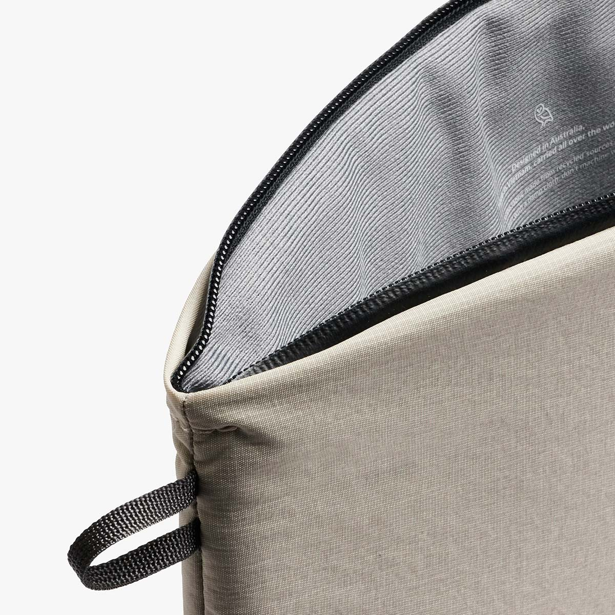 Borsa beige con zip nera, interno grigio a righe. Manico.