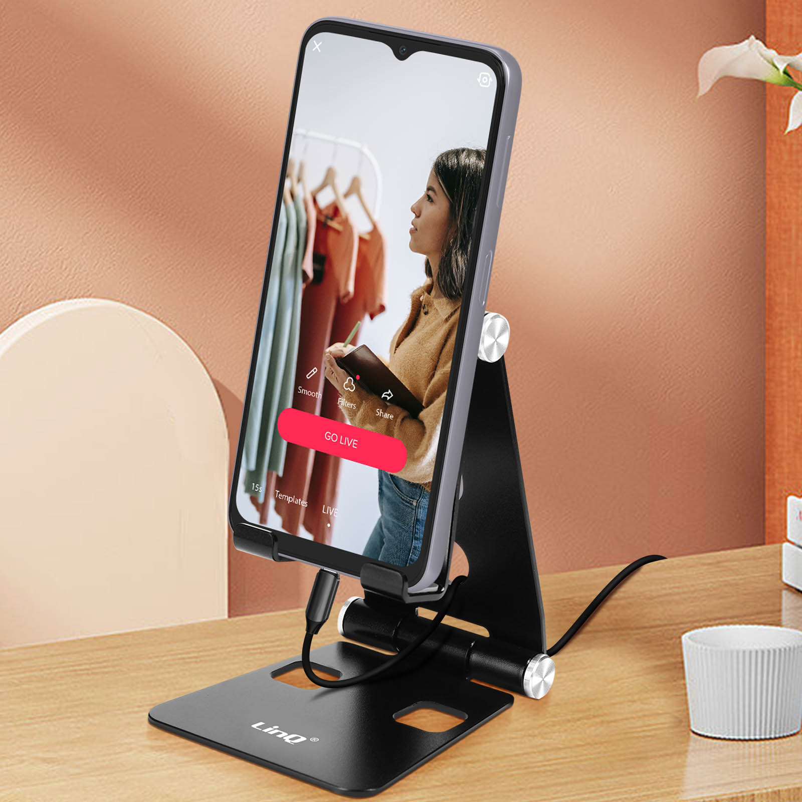 Un telefono su un supporto mostra una donna che sceglie vestiti.