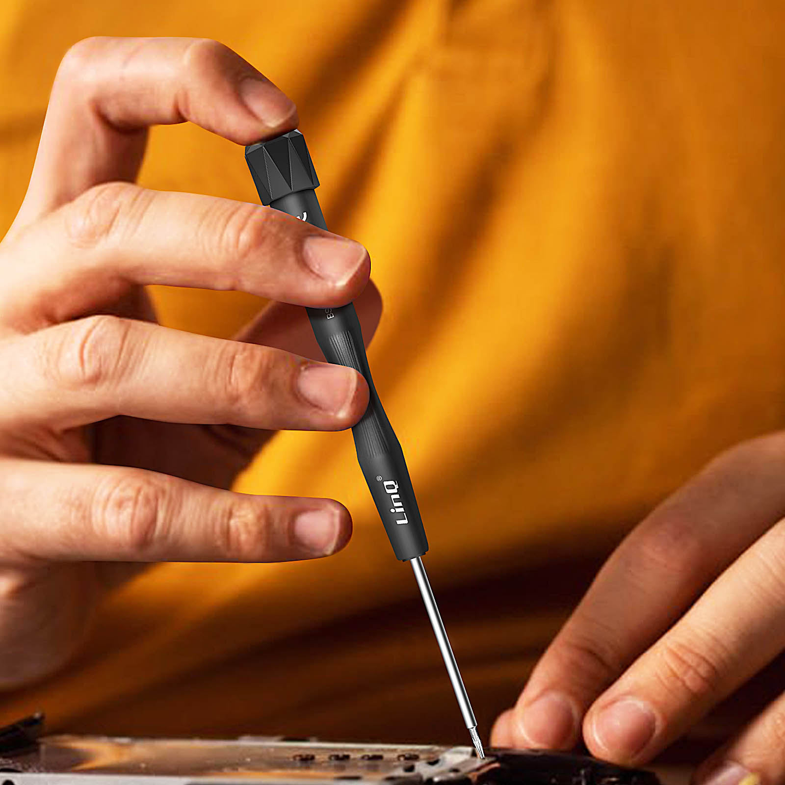 Person repariert Elektronik mit einem kleinen Schraubendreher.