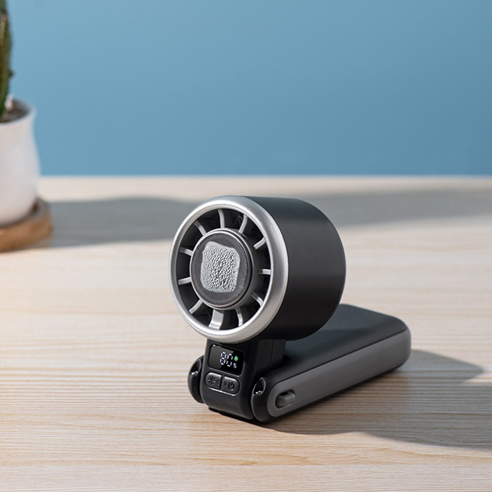 Un ventilador negro con borde plateado sobre mesa de madera, pantalla muestra 80%.