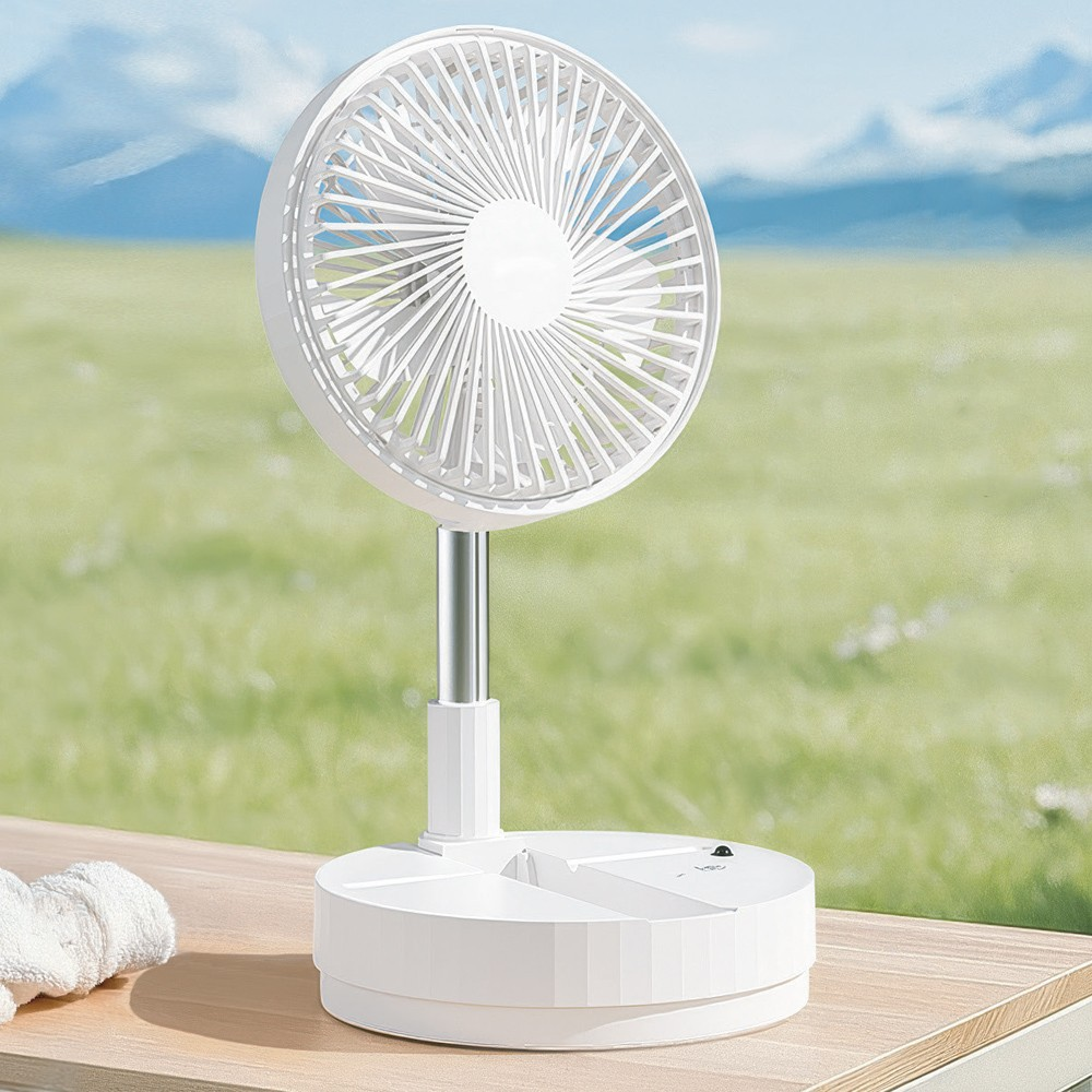 Un ventilador portátil blanco sobre mesa de madera, con campo verde y cielo borrosos.