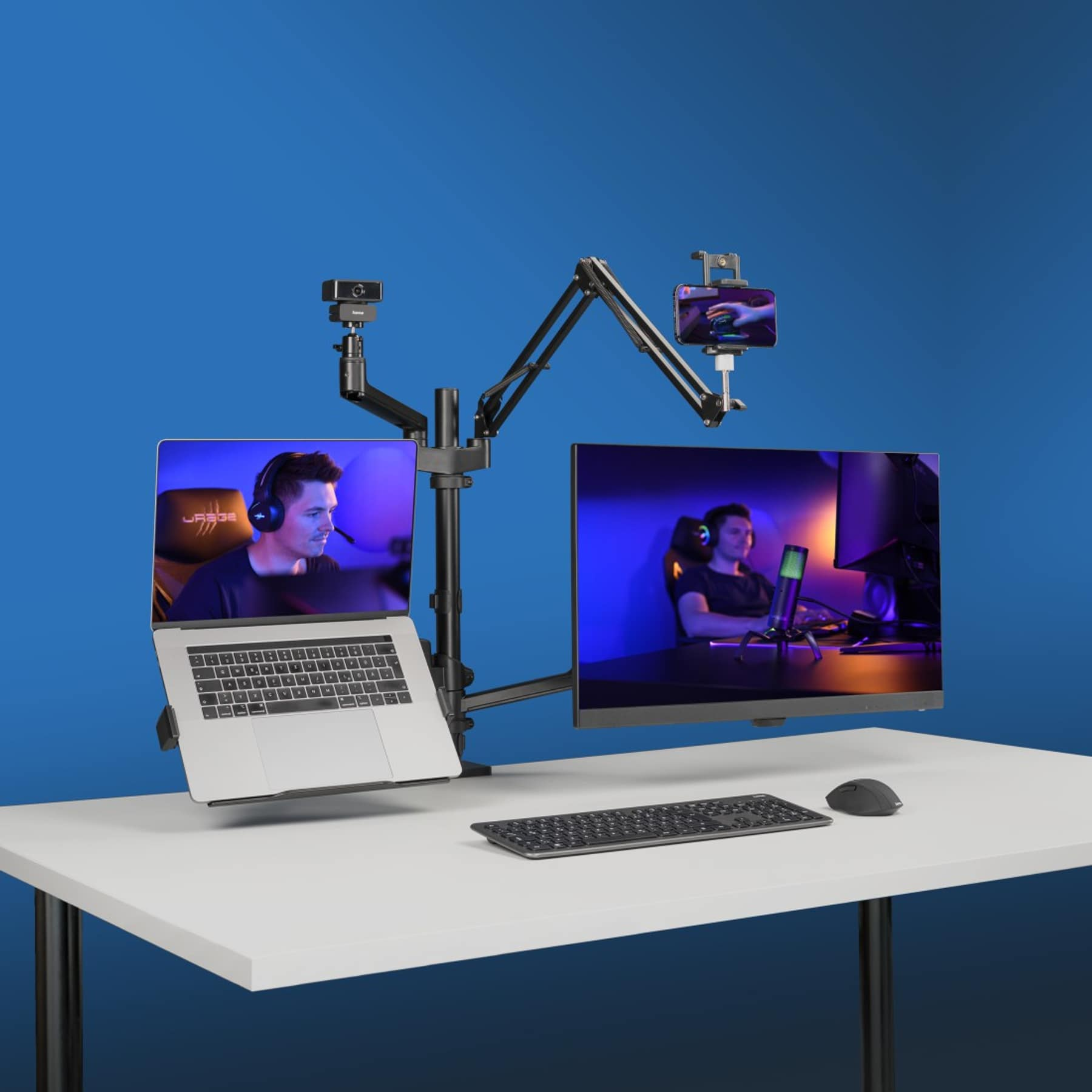 Configuration de bureau avec deux moniteurs, ordinateur portable, webcam, téléphone et clavier.