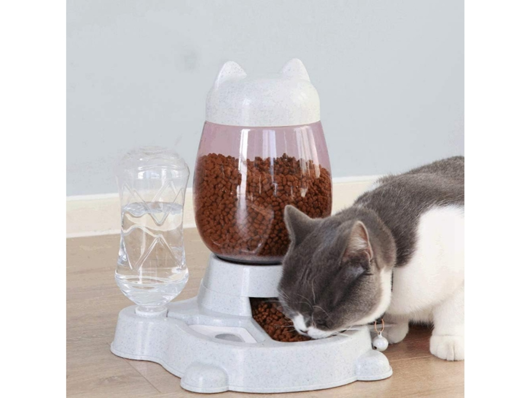 Eine Katze frisst aus einem Futterspender mit Wasserbehälter.