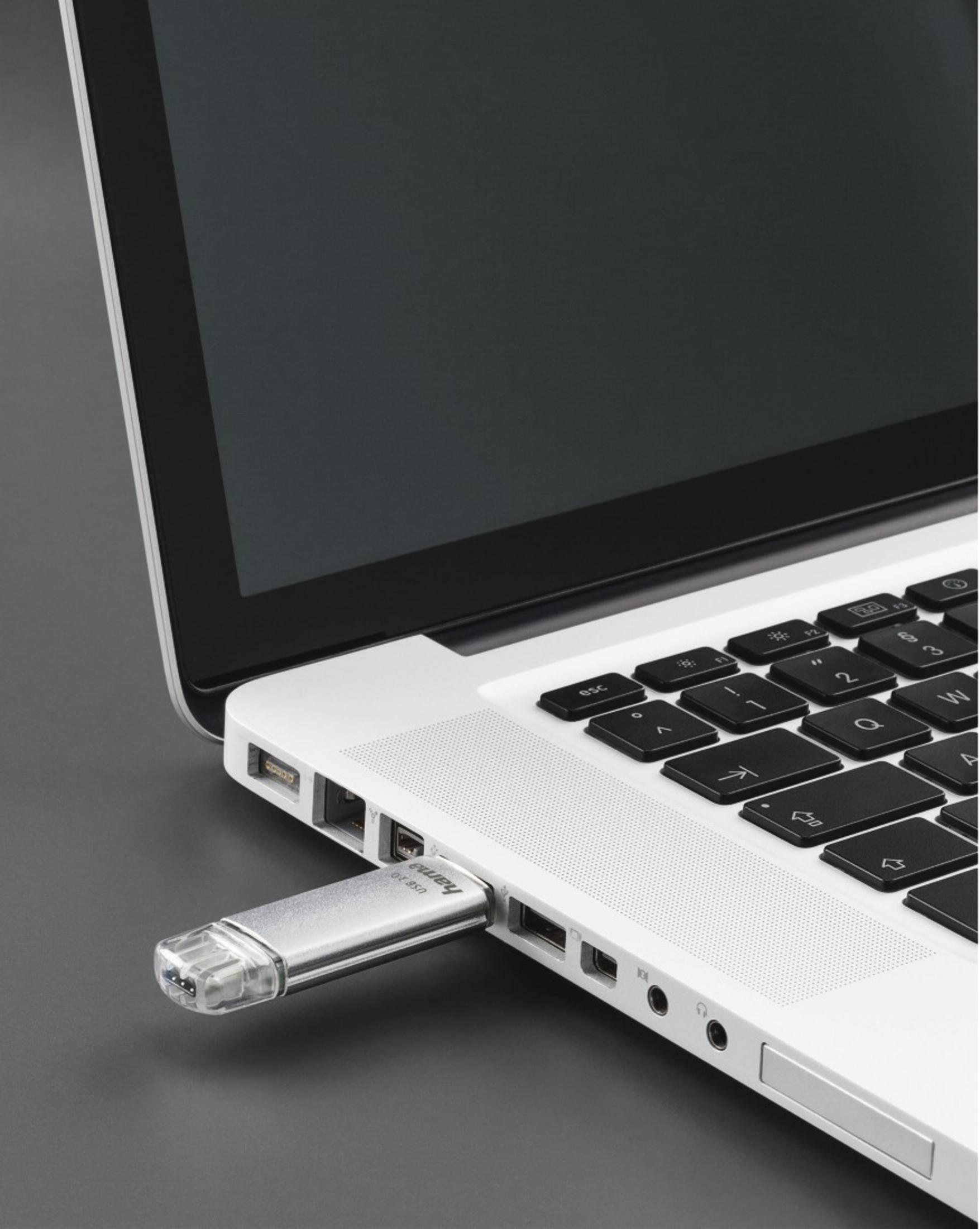 Un'unità USB argentata è collegata a un laptop bianco.