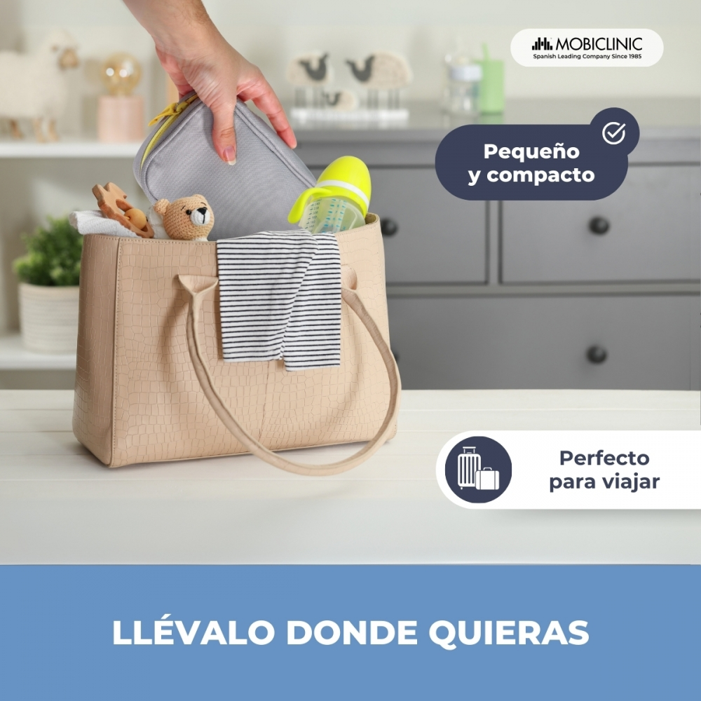Una mano mete una bolsa de pañales con artículos de bebé en un bolso.