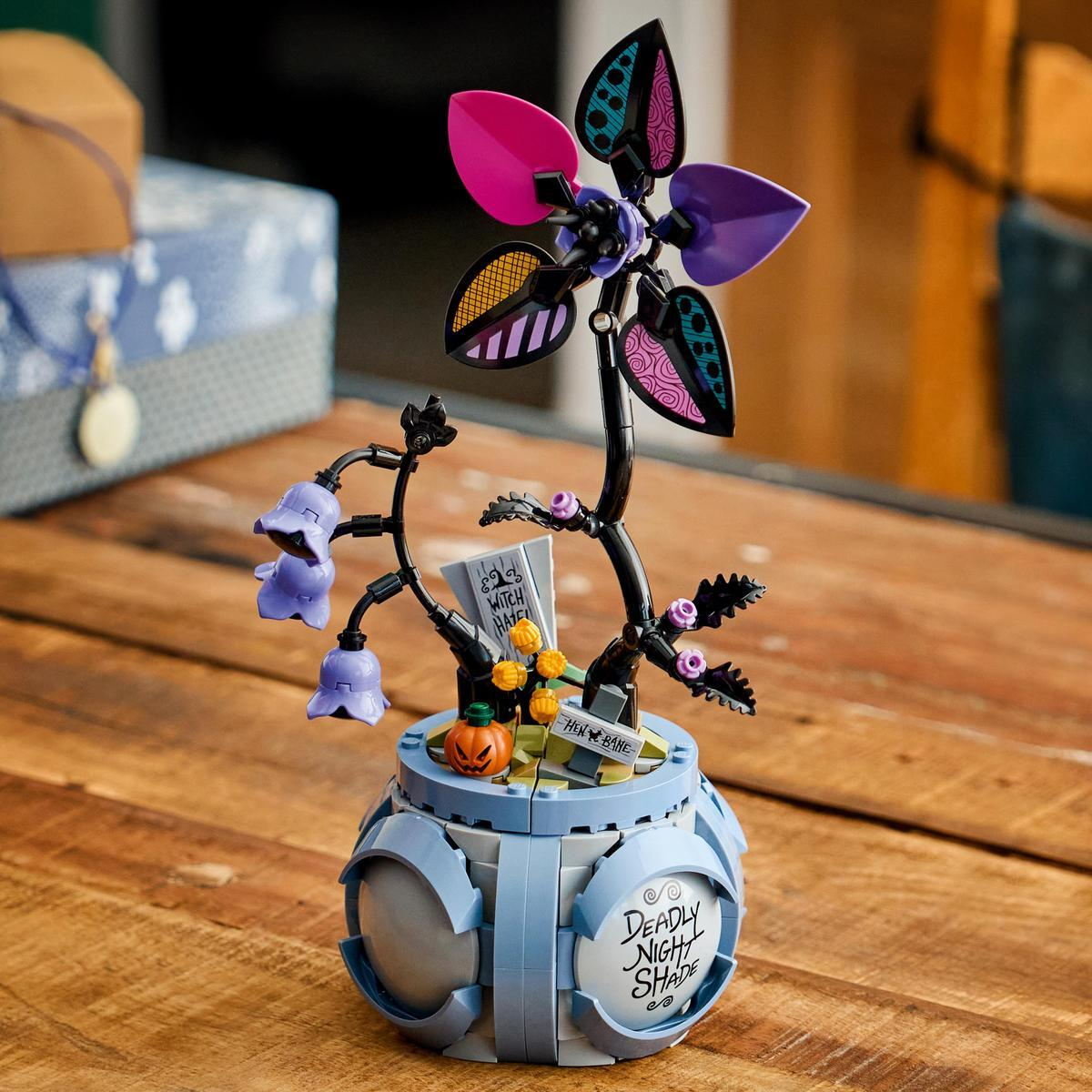 Un modello LEGO con campanula viola, zucca e cartello in un contenitore blu.