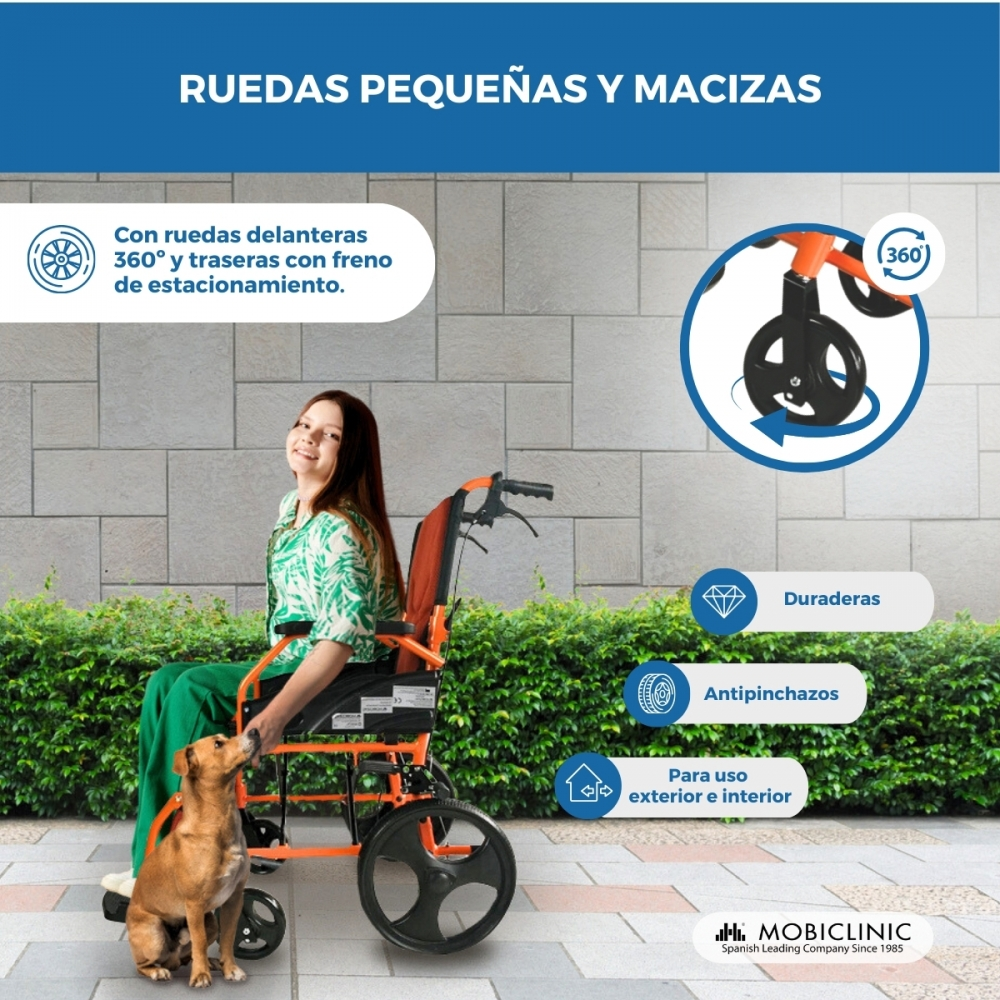 Una niña sentada en una silla de ruedas naranja con un perro delante. Las ruedas son pequeñas y macizas.