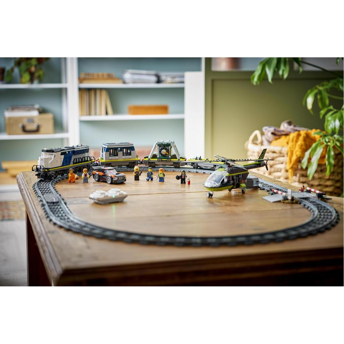 Tren de juguete con helicóptero, coche y figuras en mesa de madera.