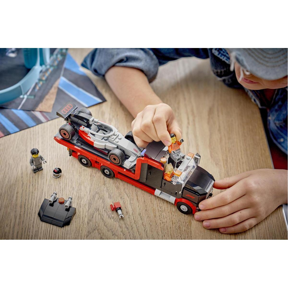 Un niño construye un transportador de coches Lego con un camión rojo y negro y un coche de carreras.