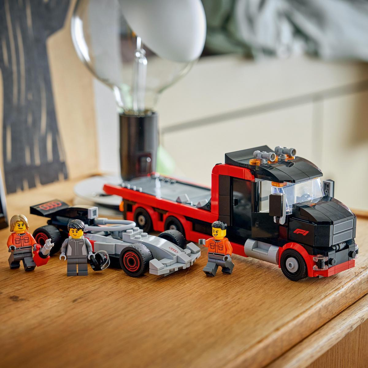 Figuras de Lego junto a un camión rojo y negro, un coche de carreras gris y una bombilla grande.