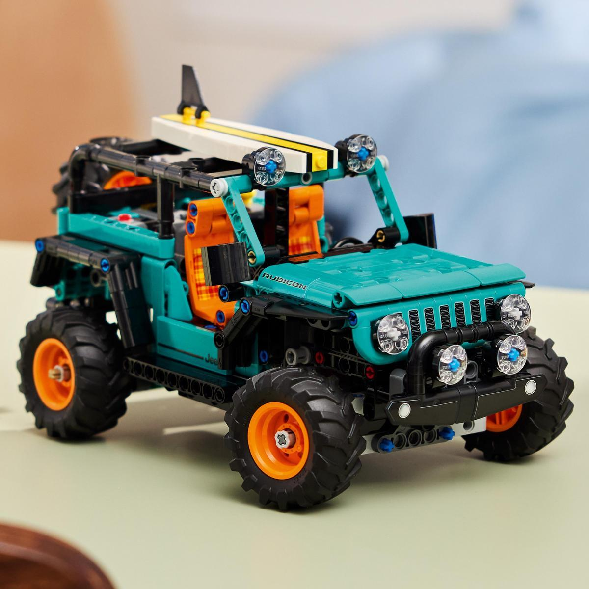 Miętowy Jeep Rubicon Lego Technic z pomarańczowymi siedzeniami i deską surfingową.