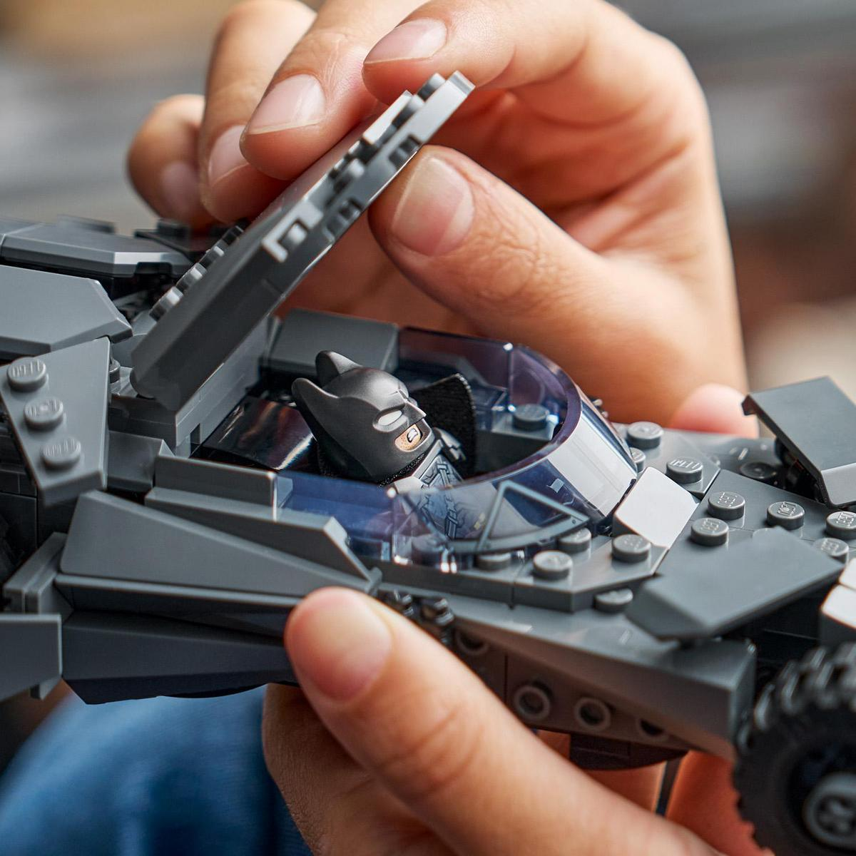 Persona che costruisce auto Lego di Batman, tenendola.