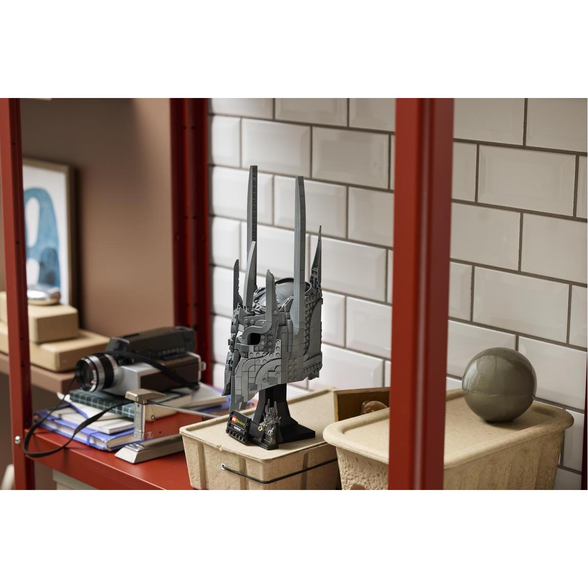 Szary hełm Lego na stojaku, z kamerą wideo i piłką w pobliżu.