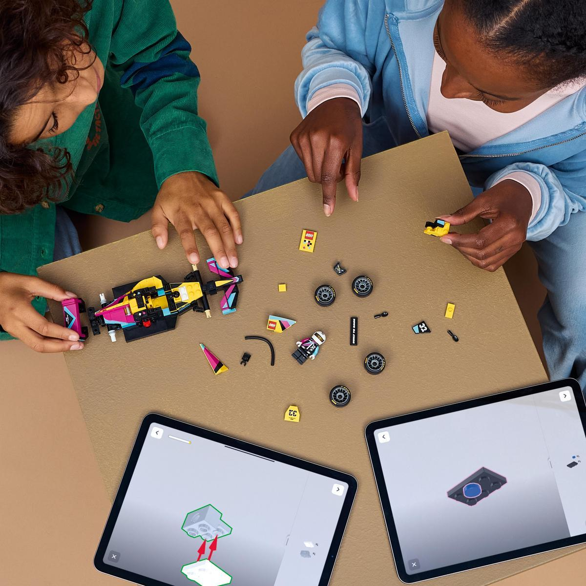 Dwoje dzieci buduje samochód Lego. Części i tablety z instrukcjami leżą na stole.