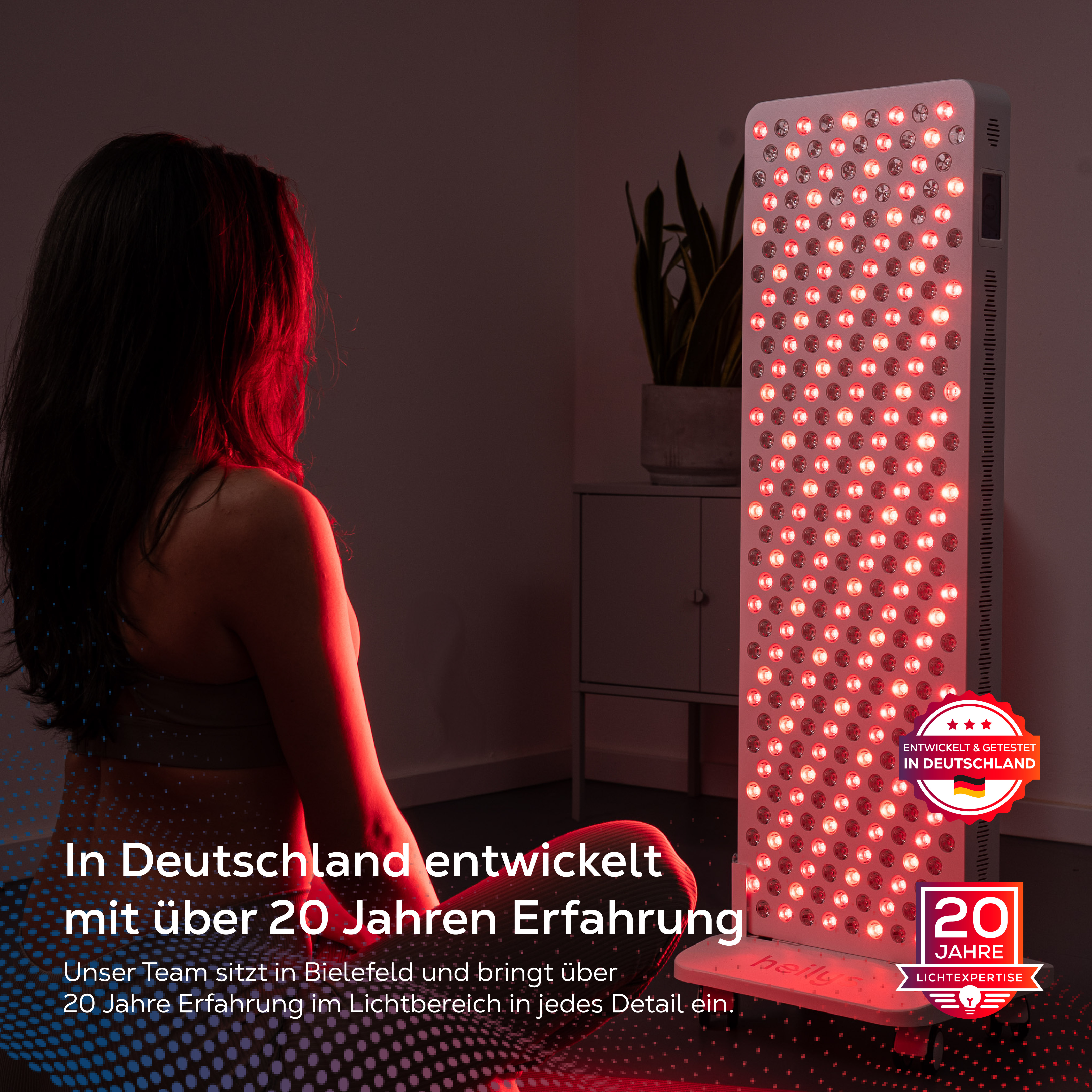 Eine Frau mit dunklem Haar sitzt vor einer roten Lichttherapieplatte. "Entwickelt in Deutschland".