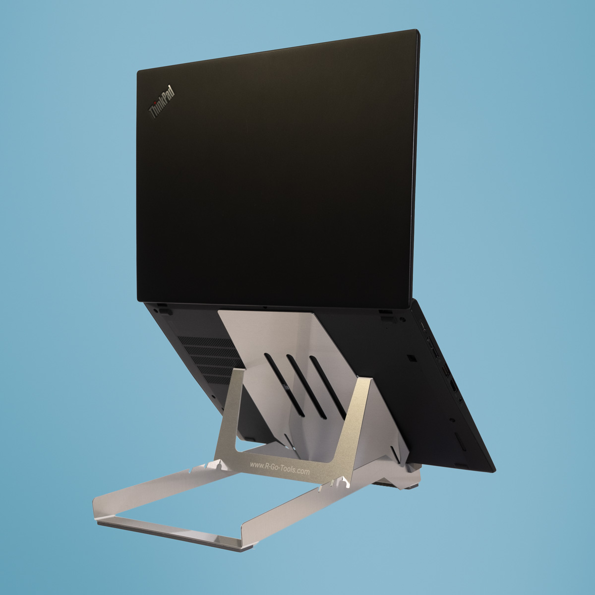 Ein schwarzer Laptop auf einem silbernen Ständer vor blauem Hintergrund.