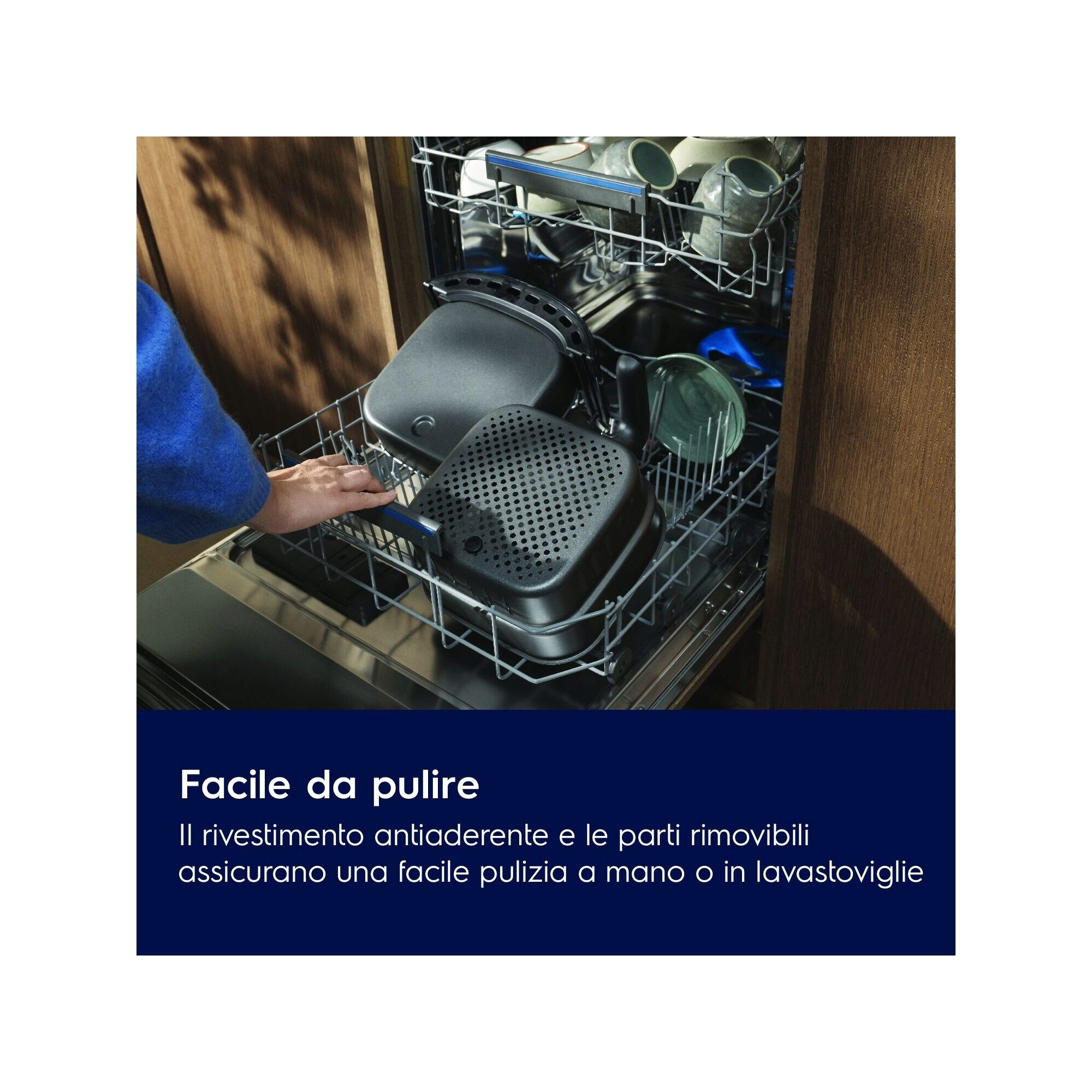 Ręka wkłada czarne naczynia do otwartej zmywarki z naczyniami.