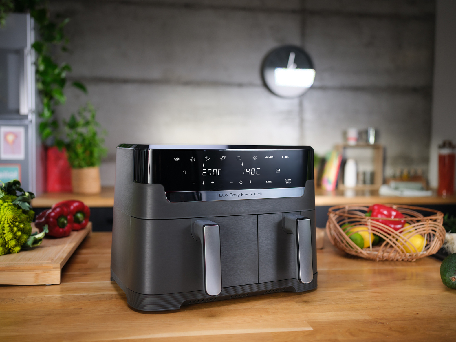 Ciemnoszara frytkownica dwukomorowa na drewnianym stole.