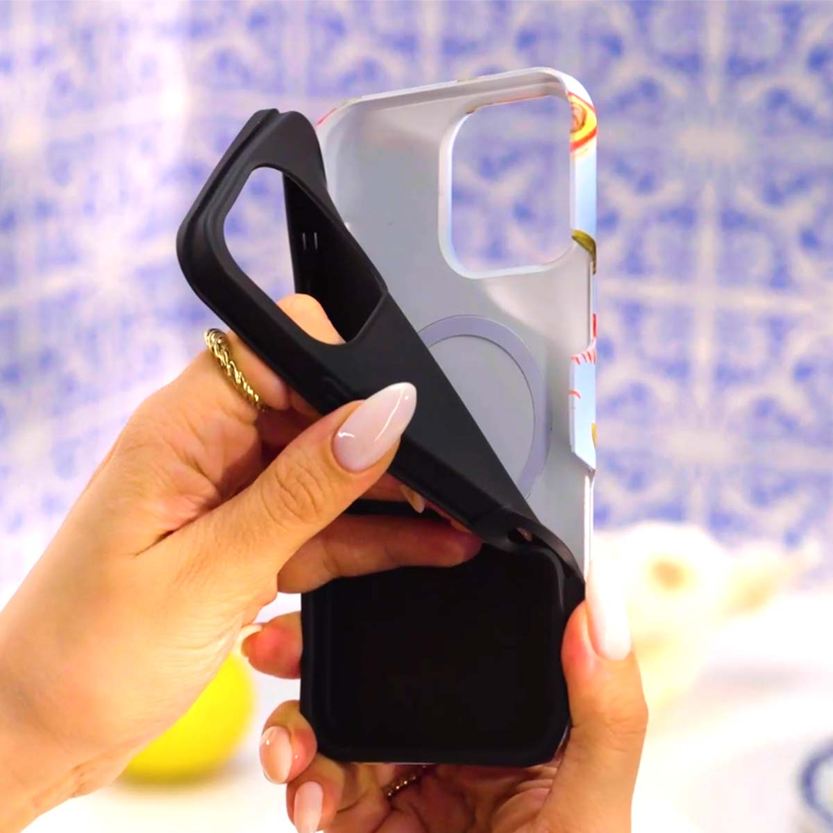 Handen tonen een zwarte telefoonhoes met kleurrijk design.