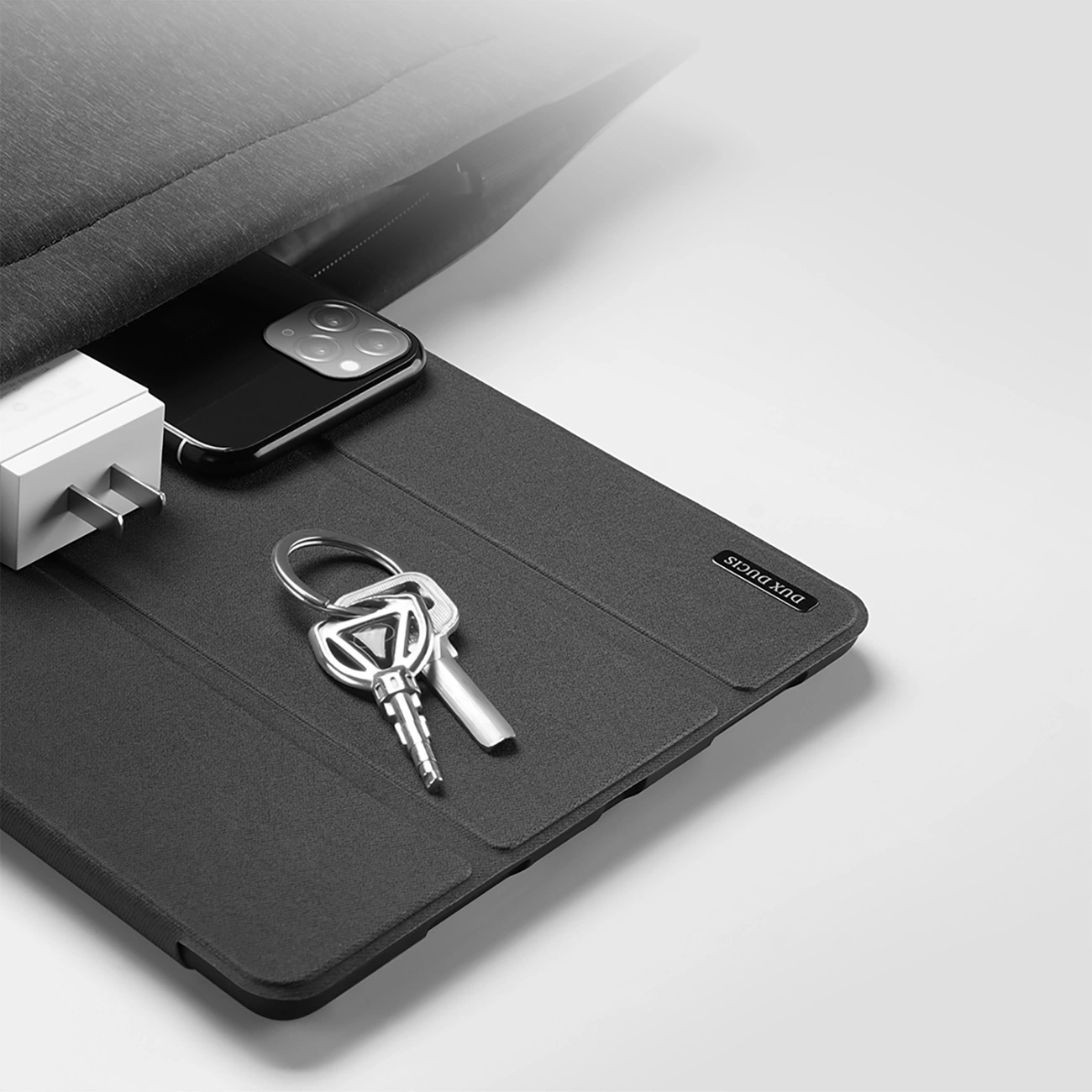 Ein Smartphone, Ladekabel, Schlüssel und eine Tasche auf einer Hülle.