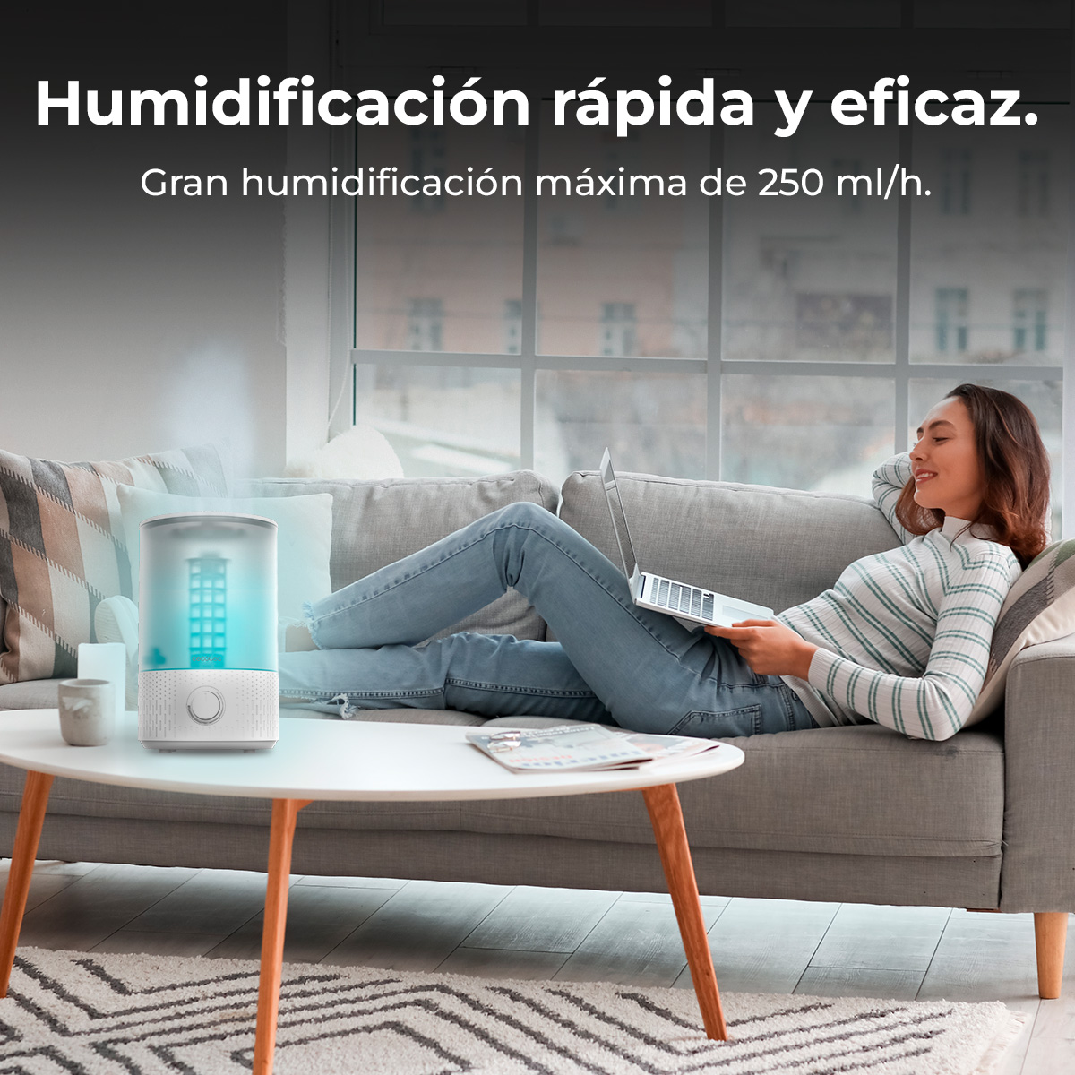 Un umidificatore con luce blu è su un tavolino vicino a una donna su un divano.