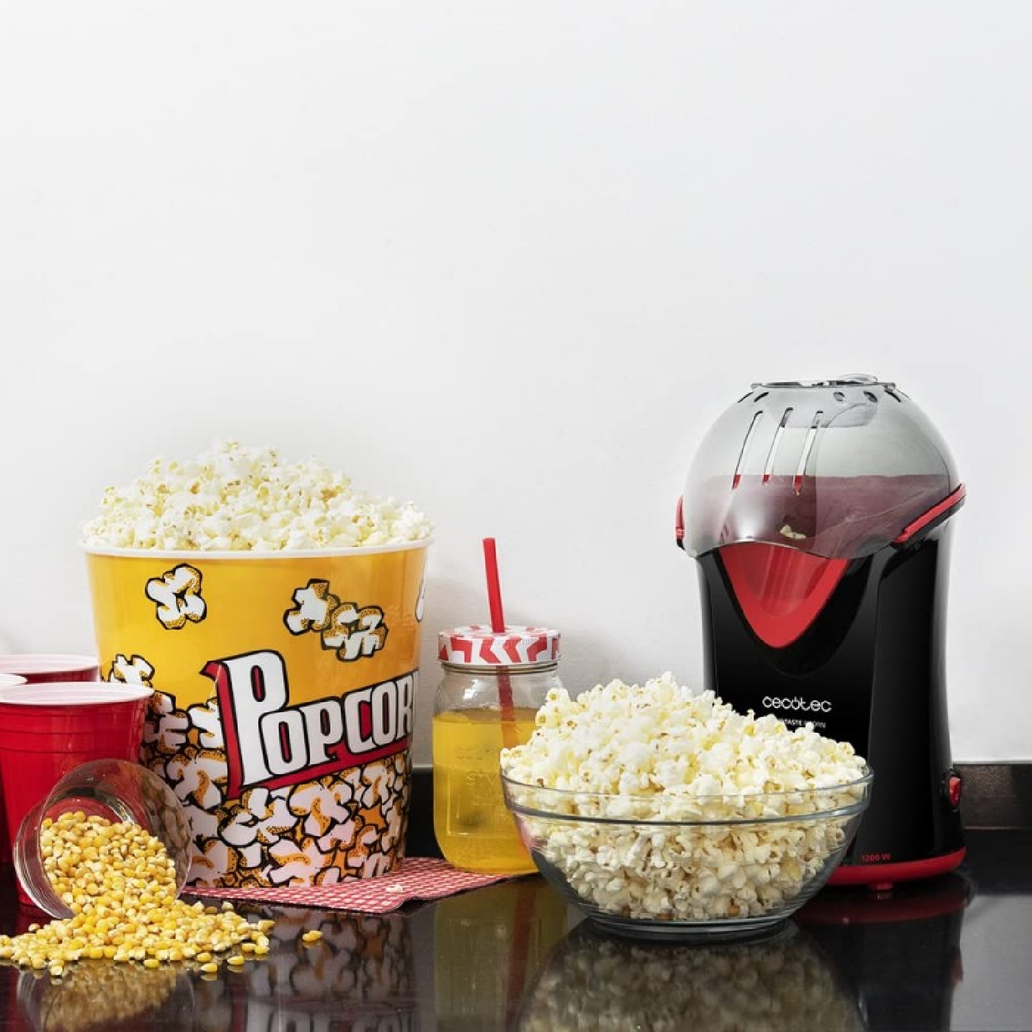 Macchina per popcorn con ciotola, secchiello per popcorn, bicchieri e mais.