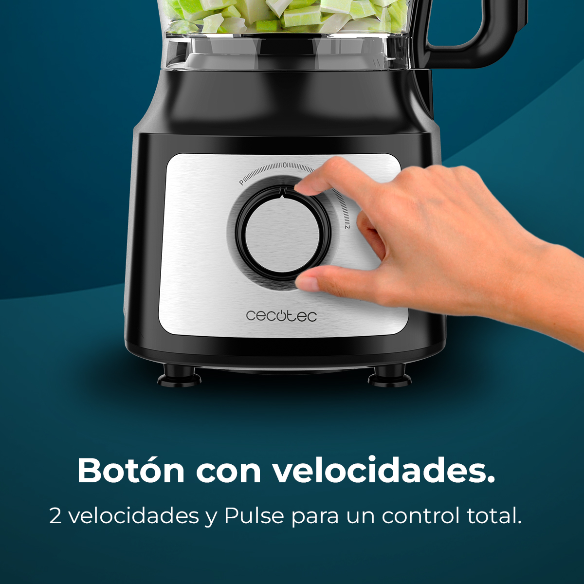 Una mano gira el selector de velocidad de un procesador de alimentos negro con verduras.