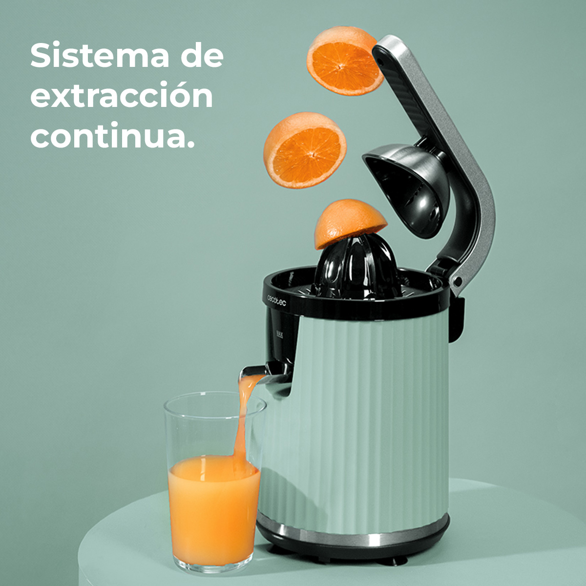 Un exprimidor verde claro extrae naranjas. El zumo de naranja fluye a un vaso.
