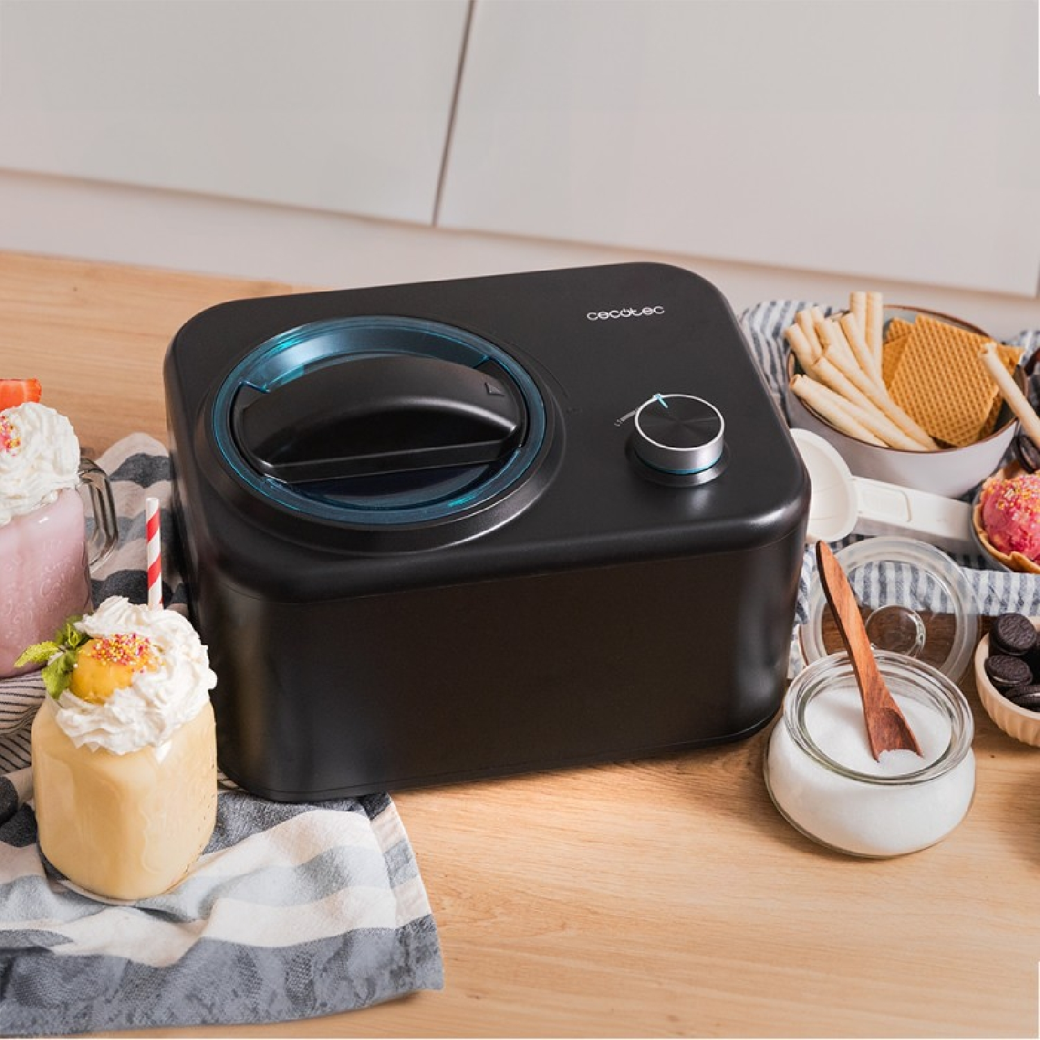 Macchina per gelato nera con anello blu, circondata da dolci e ingredienti.
