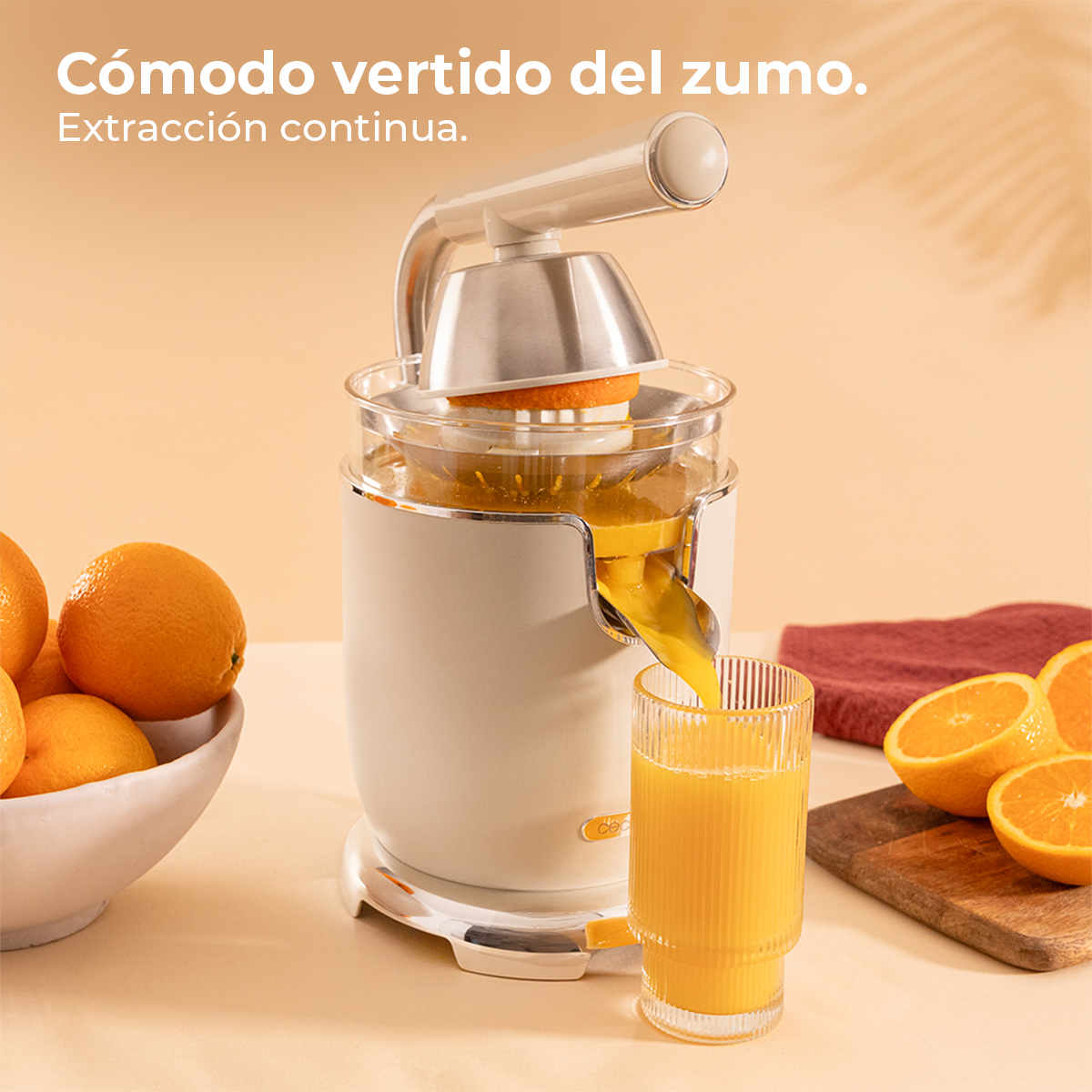 Un exprimidor eléctrico extrae naranjas. El jugo fluye hacia un vaso.