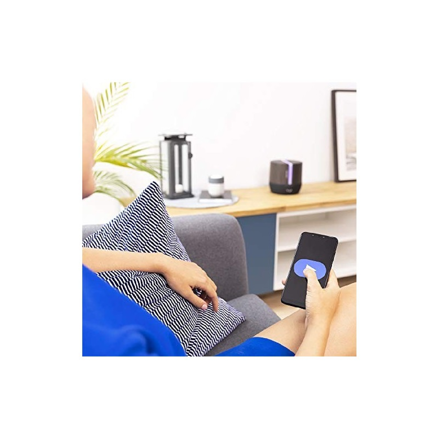 Osoba leżąca na sofie obsługuje smartfon z niebieską ikoną koła.