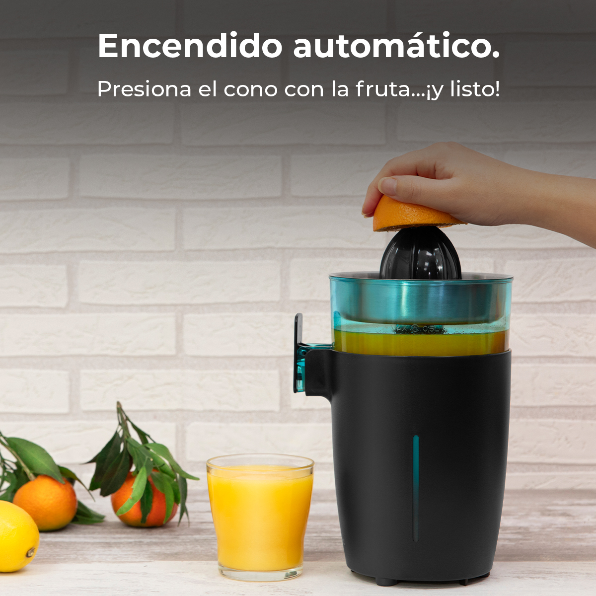 Una mano presiona una naranja sobre un exprimidor. Al lado, un vaso de zumo.
