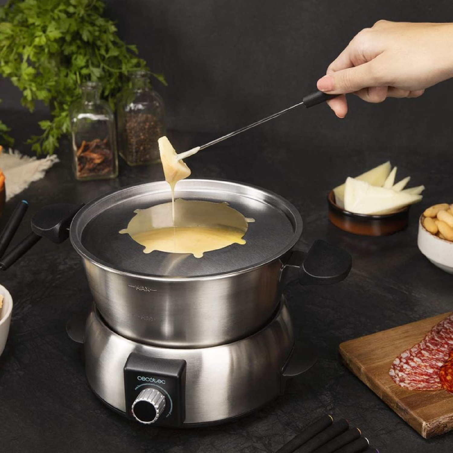 Naczynie do fondue serowego z roztopionym serem i kawałkiem chleba na widelcu.